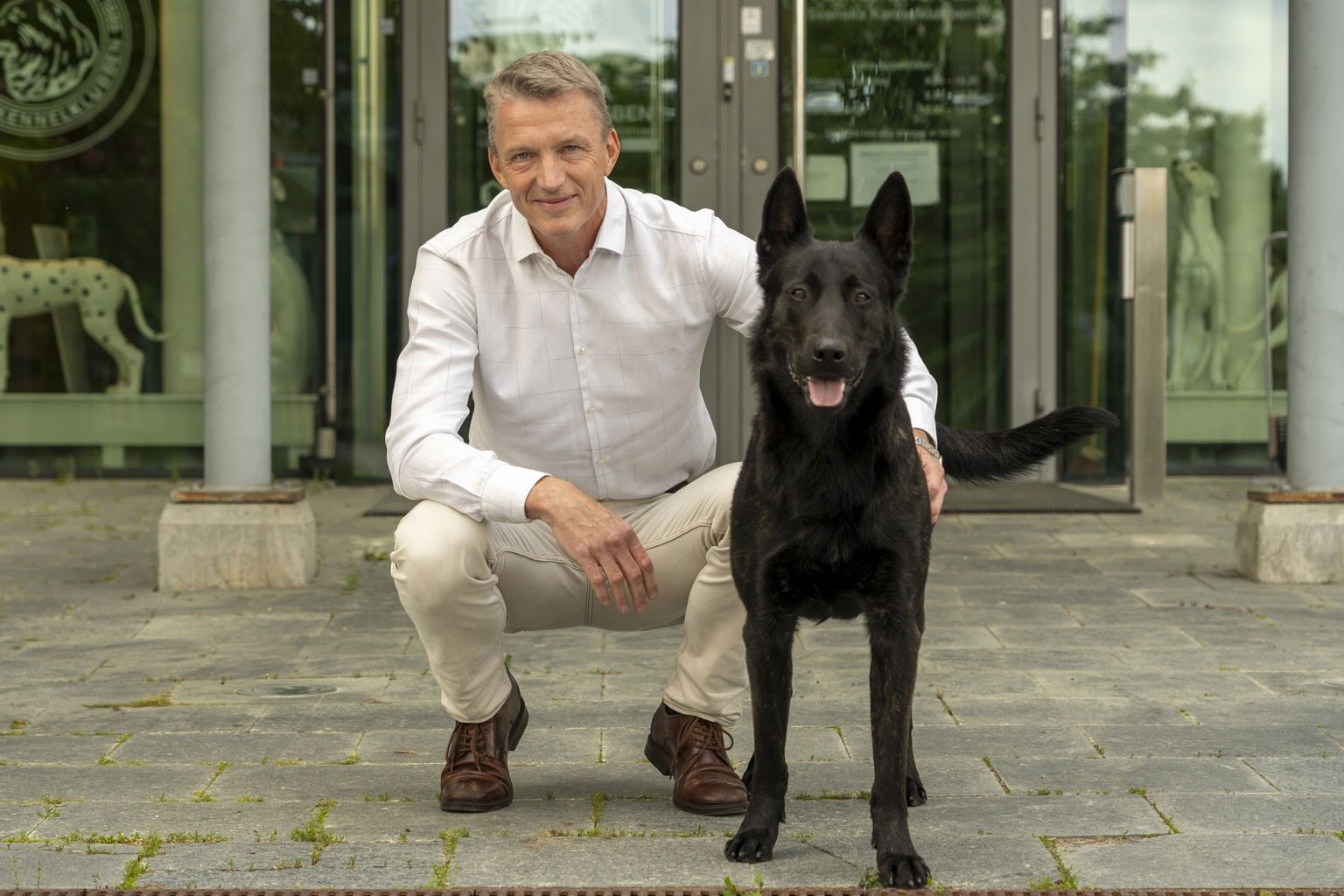 Svenska Kennelklubbens vd, Kees De Jong, sitter tillsammans med en holländsk herdehund utanför SKKs entré.