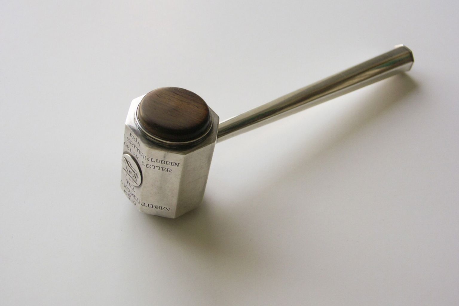 Ett ordförandeklubba i metall med en träskiva.